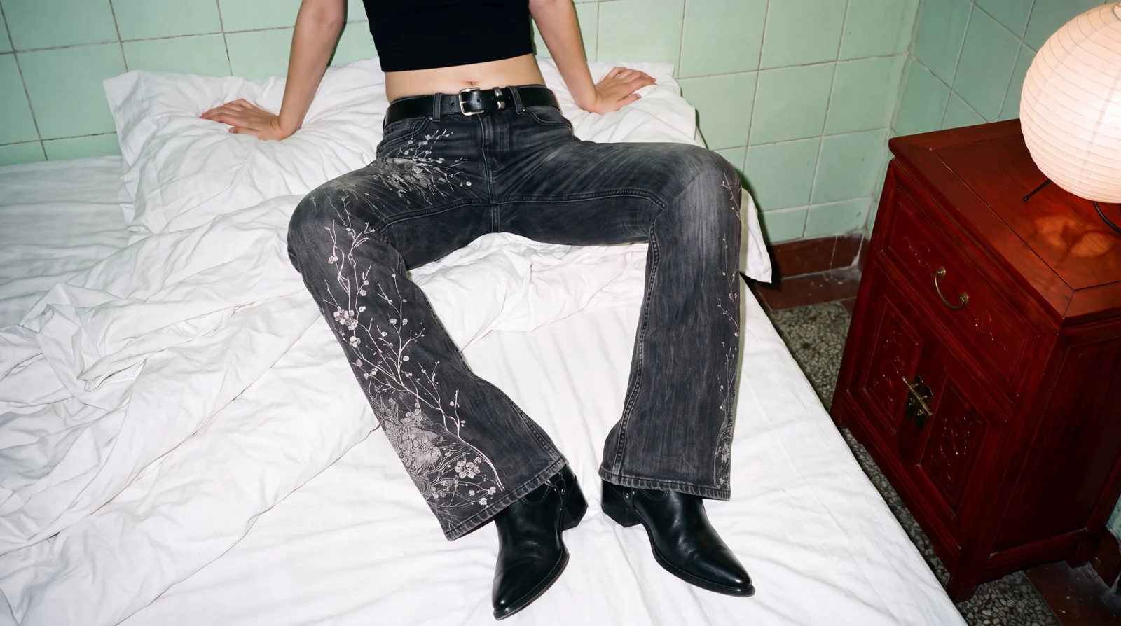 K02 YUN low rise wide leg jean, sitting on a bed, washed black denim with a laser-etched plum blossom