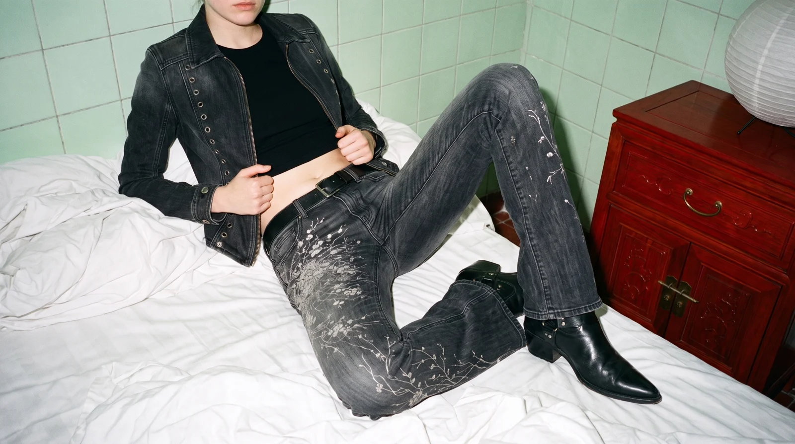 K04 YING denim jacket, worn open, reclining on a bed