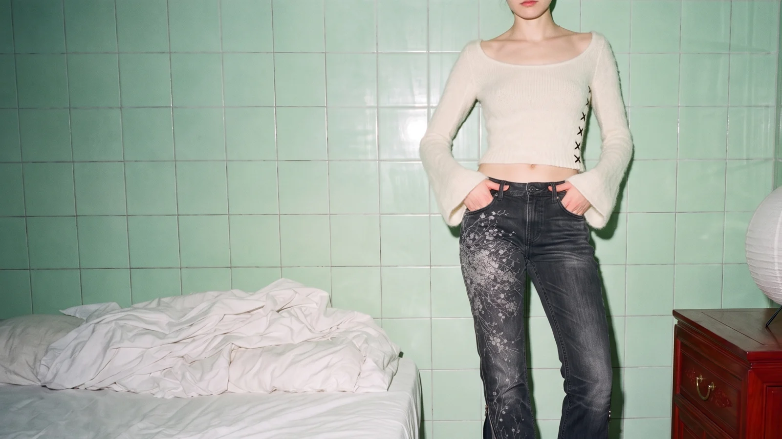 K05 CHA mohair top in ivory with black X stitches, standing against green tiles